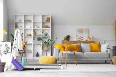 Oturma odasında havlu, su şişesi ve köpük sarmalı koşu bandı.