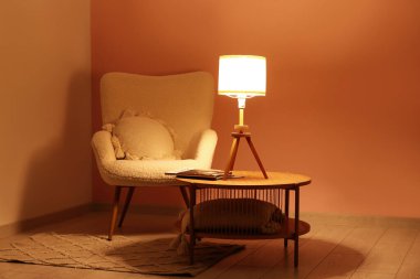 Kahve masasında parlayan lamba ve şık oturma odasında yumuşak koltuk.