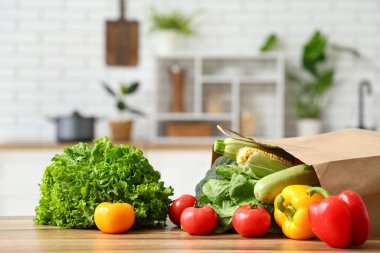 Ahşap mutfak tezgahında farklı taze sebzelerle alışveriş torbası.