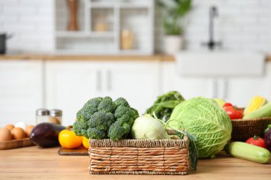 Tahta mutfak tezgahında farklı taze sebzelerle dolu bir sepet.