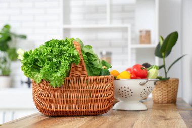 Tahta mutfak tezgahında farklı taze sebzelerle dolu bir sepet.