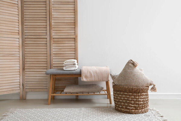 Stack of clean soft towels on soft bench near white wall