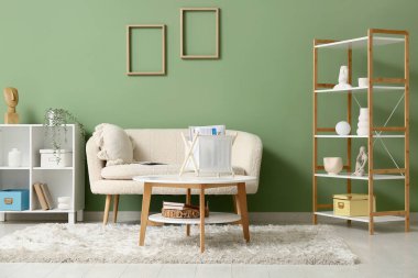 Oturma odasındaki beyaz kanepenin yanındaki sepetin üzerinde dergiler vardı.