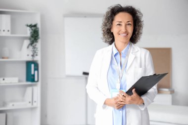 Klinikte panosu olan olgun bir kadın doktor.