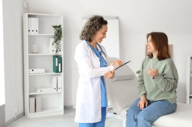 Klinikte hastayla çalışan olgun bir kadın doktor.