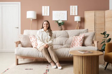 Evinde tablolarını asan genç bir kadın.