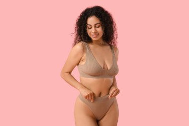 Pembe arka planda şık iç çamaşırlı güzel, mutlu, Afro-Amerikan kadın.