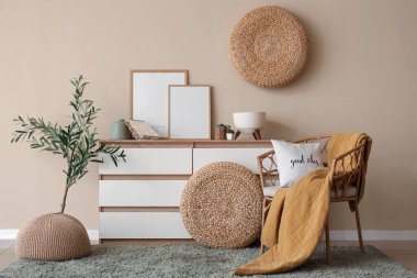 Güzel oturma odasının içinde çekmeceler, rahat koltuklar, resimler ve zeytin ağacı var.