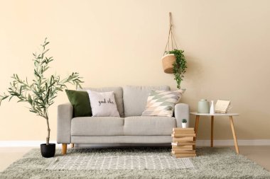 Güzel oturma odasının içinde rahat bir kanepe, sehpa, yastıklar ve zeytin ağacı var.