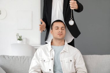 Cep saati olan kadın psikolog ofisteki genç adamı hipnotize ediyor.