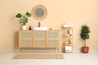 Seramik lavabo ve çekmeceler banyoda bej duvarın yanında.