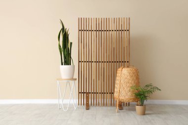 Kahve sehpası, ev bitkisi, rattan sepeti ve katlanır ekranı olan güzel bir oda.