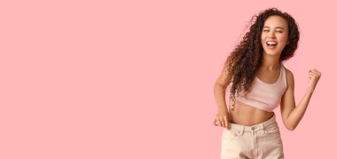 Pembe arka planda bol kot pantolonlu, mesaj atmak için yeri olan mutlu genç Afro-Amerikalı kadın. Diyet kavramı