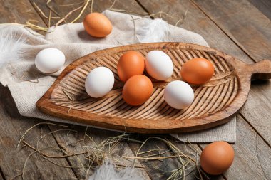 Ahşap arka planda çiğ tavuk yumurtası ve tüylü tahta.