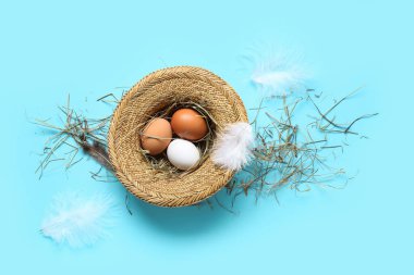 Mavi arka planda çiğ tavuk yumurtası olan hasır kase.