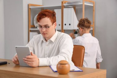 Tablet bilgisayarı ve küçük oğluyla çalışan genç bir işadamı.