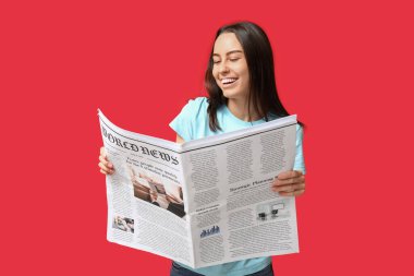 Kırmızı arka planda gazetesi olan güzel genç bir kadın.