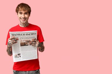 Pembe arka planda gazetesi olan yakışıklı bir genç.