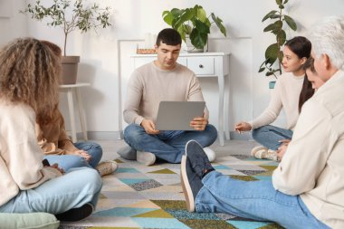 Grup terapisinde dizüstü bilgisayarı olan genç adam.