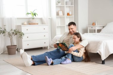 Baba yatak odasında kızına masal okuyor.