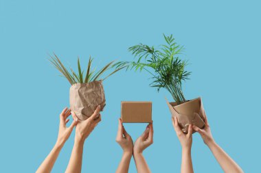 Taşınan kutuya ve mavi arka plana sarılı bitkilere sahip kadınlar