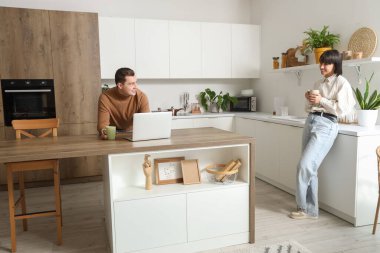 Mutfakta kahve ve dizüstü bilgisayarı olan genç bir çift.
