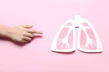 Pembe arka planda kağıt ciğerlere bakan kadın el.