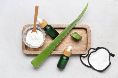 Aloe vera yapraklı ahşap tahta, arka planda gerekli yağ ve enzim tozu şişeleri