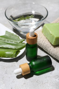 Arkaplanda yağ, havlu, sabun ve aloe vera şişeleri var.