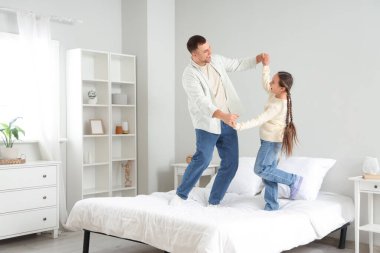Babası ve kızı yatak odasında dans ediyorlar.
