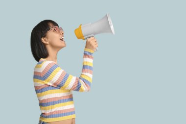 Mavi arka planda megafonu olan genç bir kadın.