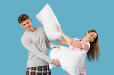 Mavi arka planda pijamalı genç bir çift kavga ediyor.