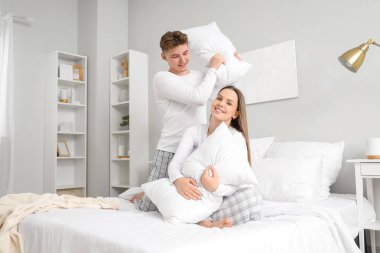 Genç çift yataklarında yastık kavgası yapıyor.