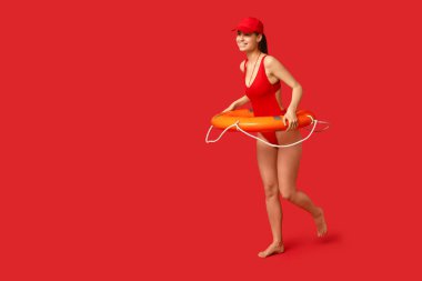 Yüzük şamandıralı ve kırmızı arka planda ıslık çalan kadın cankurtaran.