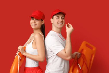 Yüzük şamandıralı cankurtaranlar ve kırmızı arka planda kurtarma tüpü.