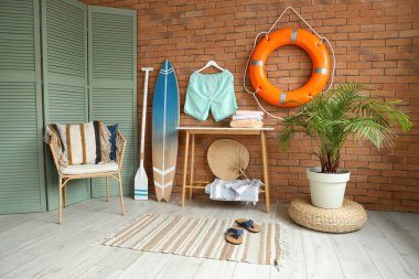 Tuğla duvarın yanında sörf tahtası ve can simidi olan modern bir oda.