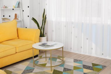 Sarı kanepe ve oturma odasının iç tarafındaki pencerenin yanındaki masa