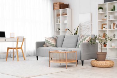 Oturma odasının içi rahat gri kanepe ve ahşap sehpa ile dolu.