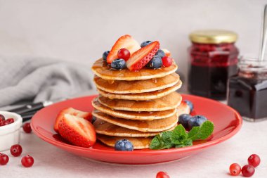 Lezzetli gözleme tabağı ve beyaz masada reçel kavanozu.