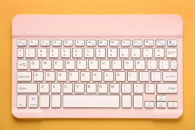 Turuncu arka planda pembe bilgisayar klavyesi. Üst görünüm