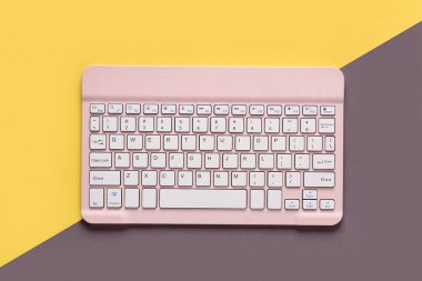 Sarı gri arka planda pembe bilgisayar klavyesi. Üst görünüm