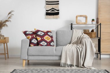 Oturma odasının içinde yastıklar ve ekoseli gri kanepe.