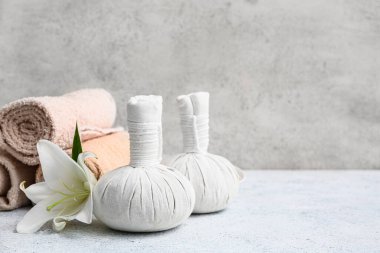 Havluları, nilüfer çiçekleri ve arkaplanda bitki torbaları olan güzel bir spa kompozisyonu.