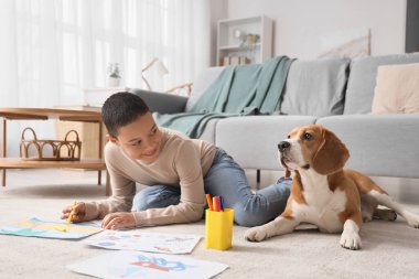 Evde sevimli bir av köpeğiyle yerde resim yapan küçük Afro-Amerikalı çocuk.