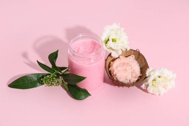 Pembe arka planda doğal vücut fırçası, çiçek ve bitki dalı olan kompozisyon