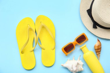 Renkli arka planda şık parmak arası terlikleri ve plaj aksesuarları olan kompozisyon