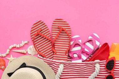 Pembe arka planda şık plaj aksesuarları olan kadın çantası.