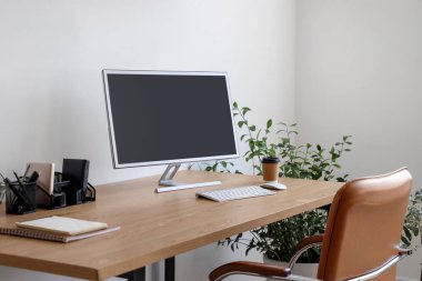 Ofisinde bilgisayar monitörü, kahve fincanı ve ev bitkisi olan modern işyeri