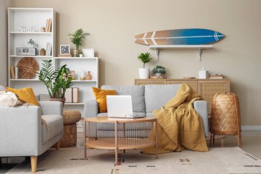 Laptop sehpası ve sörf tahtasıyla modern oturma odasının içinde.