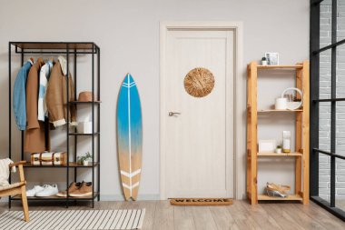 Koridorun içinde sörf tahtası, raf ve raf ünitesi var.